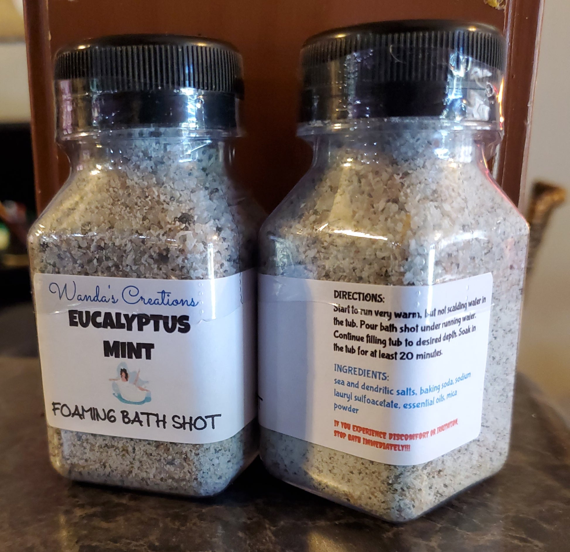 Two glass jars with labels containing directions for making a Eucalyptus Mint Foaming Bath Shot, one jar labeled 'Eucalyptus Mint' and the other with 'FOAMING BATH SHOT' text. Both jars have white and blue labels with additional text.
