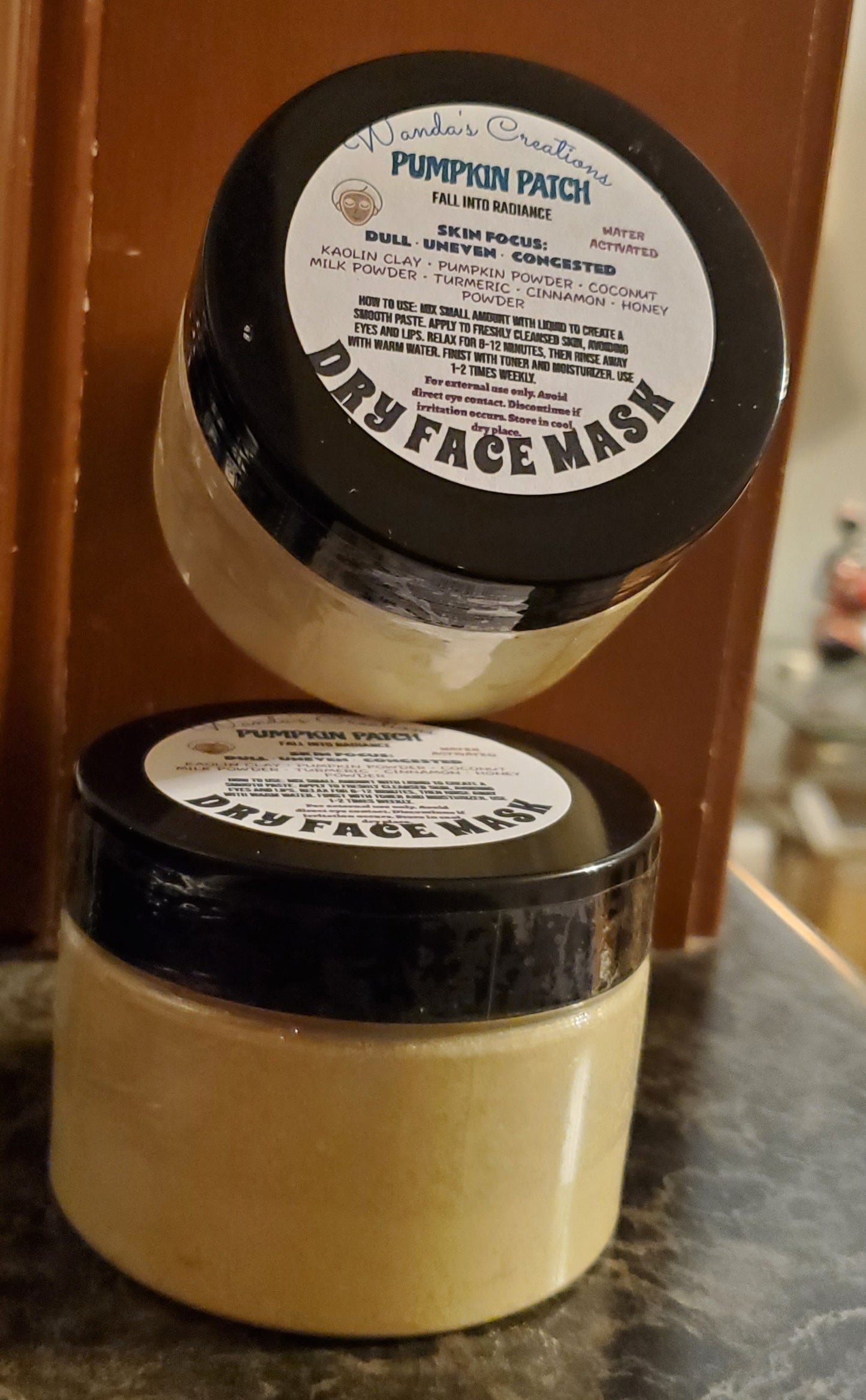Two jars of pumpkin patch dry face mask on a surface with a blurred background